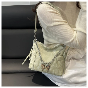 Detail of light green shoulder bag with golden butterfly buckle and silver chain strap