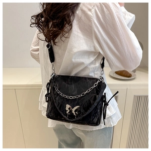Détail du sac bandoulière noir plissé avec chaîne argentée et boucle papillon