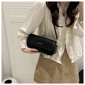 Detail of a black leather rectangular shoulder bag worn with a white lace shirt