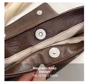 Detail shot of the magnetic snap closure on a dark brown leather tote bag with lining