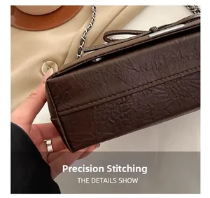 Macro shot of precision stitching and pleated texture on brown chain crossbody tote bag