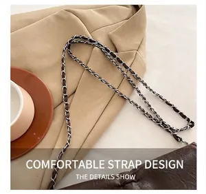 Close-up of metal chain strap on dark brown leather tote bag with elegant texture