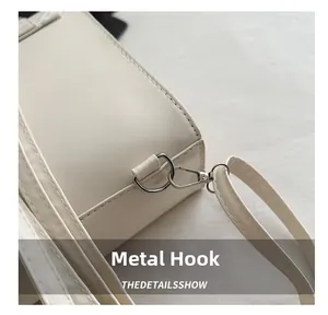 Close-up of the silver metal hook and D-ring on the textured cream leather handbag