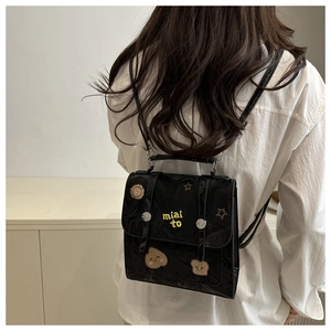 Detail of mini black backpack featuring star patches and yellow embroidery on back