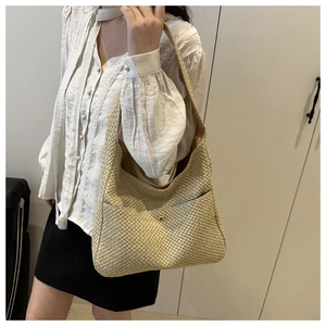 Détail du sac à bandoulière en paille tressée avec boucle magnétique et poche frontale