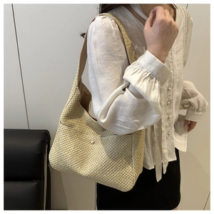 Dettaglio della borsa a spalla in paglia intrecciata con bottone di perla e design a mezzaluna