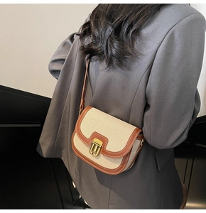 Retro canvas saddle bag with brown faux leather trim worn over a grey blazer jacket
