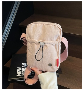 Detail of pink nylon mini crossbody bag with drawstring pocket and adjustable strap