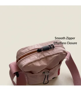 Close-up detail of the smooth zipper and durable nylon fabric on a pink crossbody bag