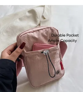 Detail of pink nylon crossbody bag with adjustable drawstring pocket and wide shoulder strap