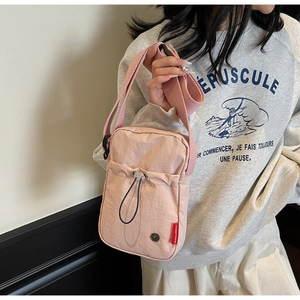 Close-up of pink nylon crossbody bag with drawstring detail on a female model