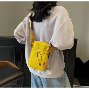 Detail view of the yellow canvas crossbody bag showing the adjustable strap on a model