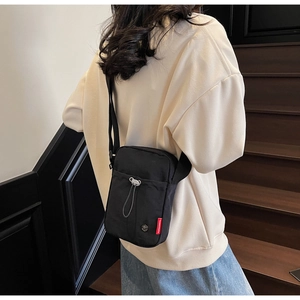 Close-up of black crossbody bag on model featuring durable nylon and silver zippers