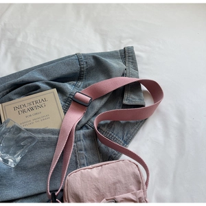 Pink nylon crossbody bag detail with adjustable wide strap and front pocket on fabric