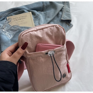Pink nylon crossbody bag detail with drawstring front pocket and matching leather wallet