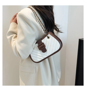 Détail du sac bandoulière matelassé blanc avec bordure marron et chaîne dorée