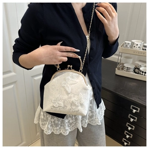 Détail du sac vintage blanc avec broderie papillon et texture de dentelle fine
