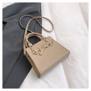 Détail d'un sac à main beige élégant avec nœud stylé et finitions métalliques dorées