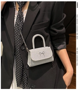 Detailed view of silver glitter mini crossbody bag with metal bow and chain strap