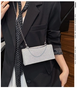 Silver sequin evening clutch bag with metal handle and chain strap on a model
