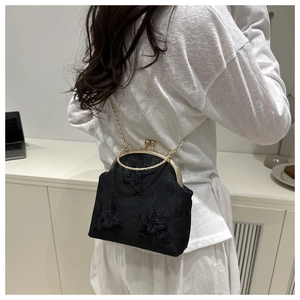 Détail de broderie papillon et fermoir doré vintage sur sac en jacquard noir