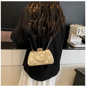 Detail of evening clutch bag featuring gold lace embroidery and crown metal clasp