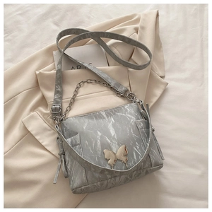Detail of silver pleated texture shoulder bag with metallic butterfly buckle and chain strap