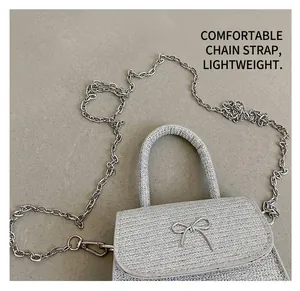 Close-up of silver-grey woven bag with metal bow buckle and chain shoulder strap