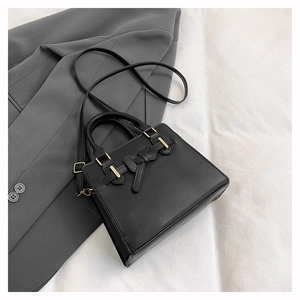 Détail du nœud noir élégant et des finitions dorées sur le sac à main en cuir