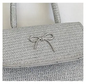 Detail of silver glitter crossbody bag with metallic bow clasp and textured surface