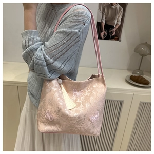 Detail of pink embroidered tote bag featuring butterfly patterns and elegant tassel charm