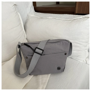 Detail of grey nylon crossbody bag with adjustable wide strap and metallic logo accent