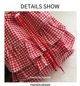 Close-up of red and white gingham fabric with layered ruffles and red drawstrings
