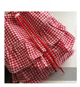 Close-up of red and white gingham fabric with layered ruffles and red drawstrings