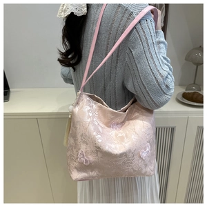 Pink lace tote bag with 3D butterfly embroidery detail shown on shoulder of a model