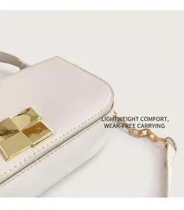 Detailopname van witte leren handtas met elegante gouden vierkante sluiting en ketting