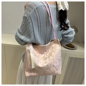 Detail of pink embroidered tote bag featuring butterfly patterns and ivory side tassel