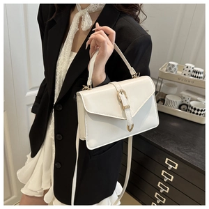 Close-up of minimalist white leather crossbody bag with champagne gold metal buckle