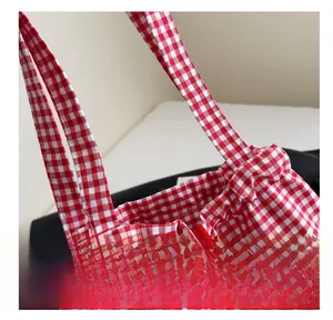 Detailed view of red and white gingham canvas tote bag with reinforced stitching and ruffle edges