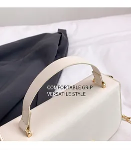 Detail van witte leren handtas met gouden D-ringen en elegante gouden kettingriem