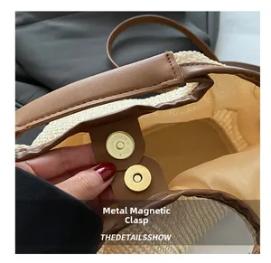 Close-up of golden magnetic buckle on beige woven tote bag with brown leather trim