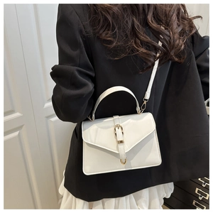 Detail of white minimalist crossbody bag with gold buckle on a model's back