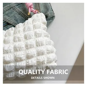 Detail of white bubble texture fabric with pink knotted handle and gold metal accents