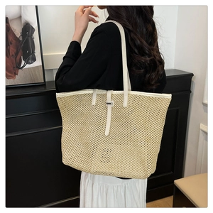 Detail of woven straw tote bag featuring white leather straps and textured pattern