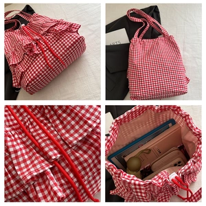 Detail view of red gingham tote bag showing ruffled edges and drawstring closure