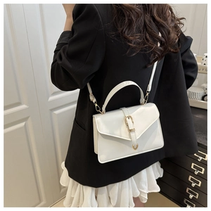 Detail of white leather crossbody bag featuring V-shaped flap and gold buckle hardware