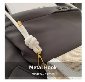 Détail du crochet doré et de la bandoulière nouée en cuir sur un sac en toile