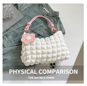 Detail of white pleated texture handbag with pink rope handle and floral charm accessory