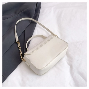 Detailed view of white faux leather crossbody bag with elegant gold chain link and flap