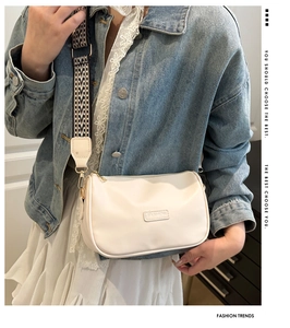 Detailed view of a white leather crossbody bag featuring a wide geometric woven strap